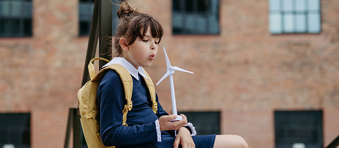 A young person blowing on a wind turnbine